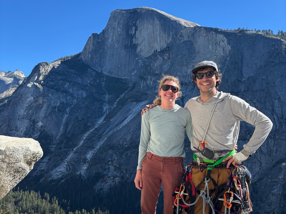 Standing with a climbing rack above Yosemite Valley, Half Dome behind